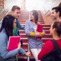 A group of young teenagers are standing on a staircase, discussing safe sex.