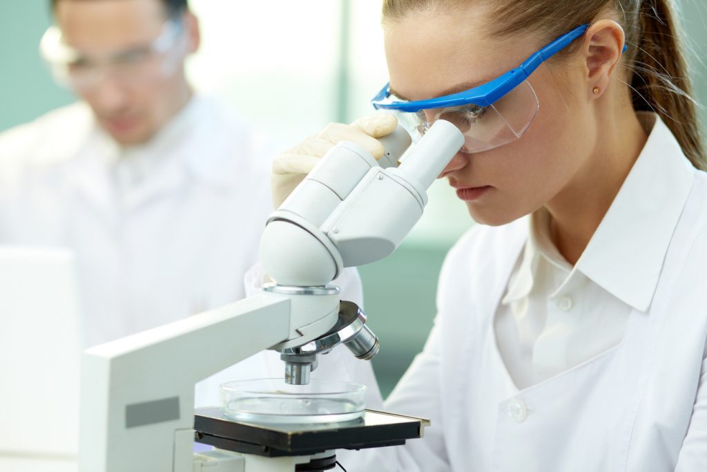 A serious clinician studying a microscope, trying to make an HIV breakthrough.