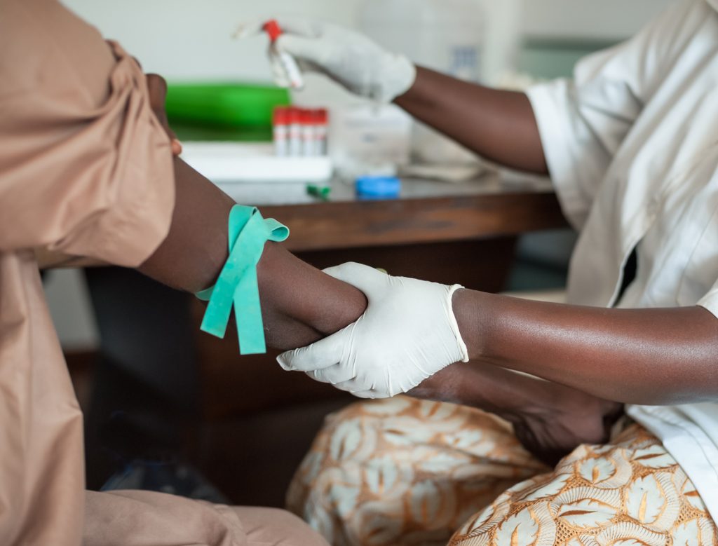African nurse is drawing blood from african to perform a test, and help in eliminating HIV.